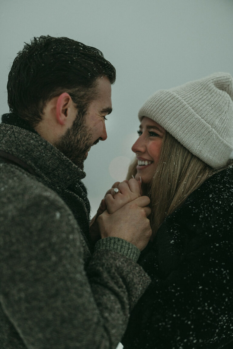 couple holding hands with engagement ring and big smile