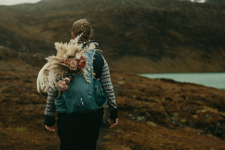 Eloping Bride with wedding bouquet in backpack in autumn nature