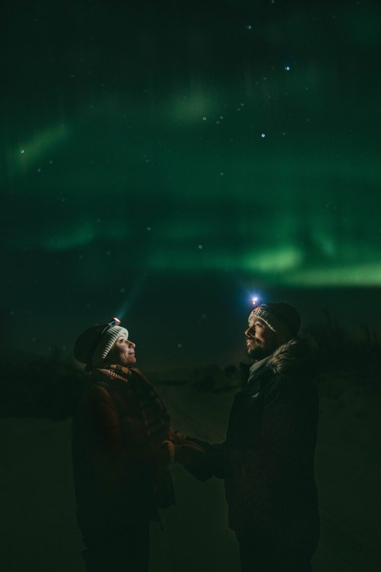 Couple holding hands with headlights during their northern lights wedding